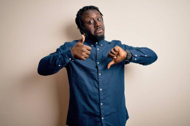 Beyaz arka planda dikilen, gündelik gömlekli, genç ve yakışıklı Afro-Amerikan bir adam. Baş parmak kaldırıyor, anlaşmazlık ve uzlaşma ifadesi sergiliyor. Çılgın çatışma