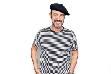 Orta yaşlı yakışıklı bir adam çizgili tişört ve beyaz arka planda Fransız beresi takıyor. Yüzünde mutlu ve havalı bir gülümseme var. Şanslı kişi..