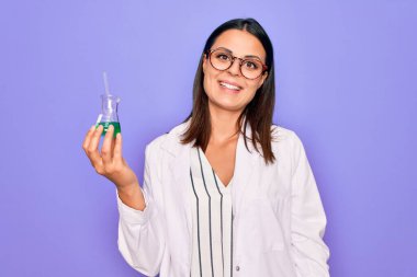 Genç, güzel, esmer bir bilim kadını. Ceket ve gözlük takıyor. Elinde deney tüpü tutuyor.