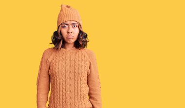 Genç, güzel, melez, yün kazak giyen, kışlık şapkalı, sıkıntılı, sinirli ve korkmuş bir kadın. hüzünlü ifade. 