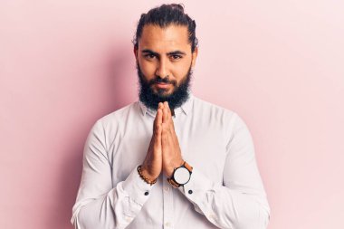 Gündelik giysiler içinde genç bir Arap ellerini birleştirip af diliyor kendinden emin bir şekilde gülümsüyor.. 