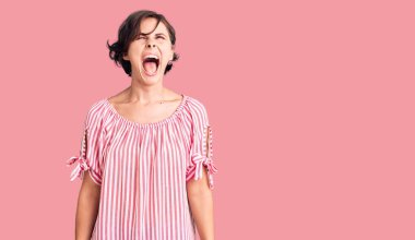 Kısa saçlı, rahat yaz kıyafetleri giyen kızgın ve kızgın çığlık atan sinirli ve öfkeli, öfkeyle bağıran güzel bir genç kadın. öfke ve agresif konsept. 