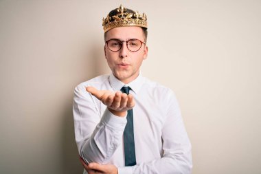 İzole edilmiş arka planda altın tacını takmış yakışıklı beyaz bir iş adamı havada el ele öpüşürken kameraya bakıyor. Güzel ve seksi. Aşk ifadesi.