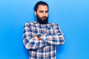 Gündelik kıyafetler giyen, kuşkucu ve gergin genç bir Arap. Yüzünde çapraz kollu tasvip etmeyen bir ifade. negatif kişi. 