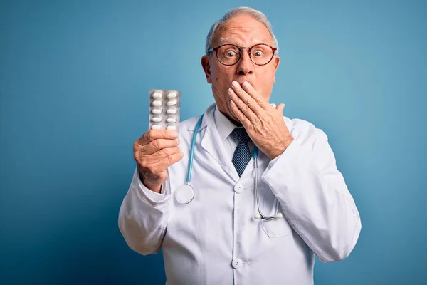 Kıdemli Gri Saçlı Doktor Elinde Mavi Arka Planda Haplar Tutuyordu — Stok fotoğraf