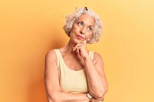 Senior grey-haired woman wearing casual clothes with hand on chin thinking about question, pensive expression. smiling with thoughtful face. doubt concept.
