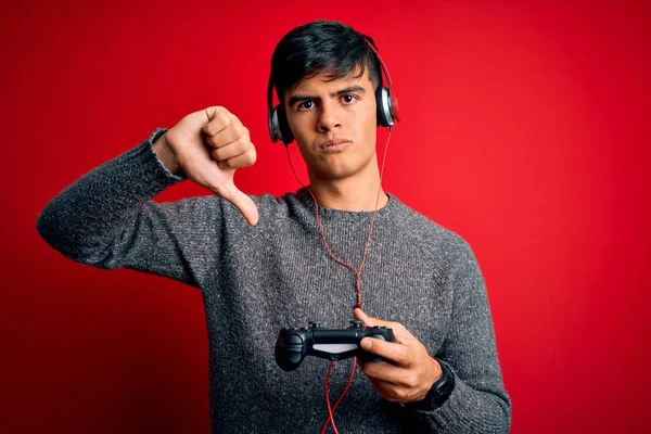잘생긴게이머 남자는 조이스틱과 헤드폰을 사용하여 비디오 게임을 하는데 얼굴을 엄지손가락을 — 스톡 사진