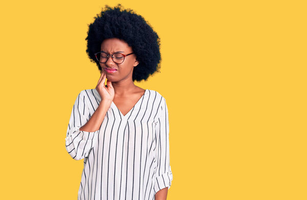 Young african american woman wearing casual clothes and glasses touching mouth with hand with painful expression because of toothache or dental illness on teeth. dentist 