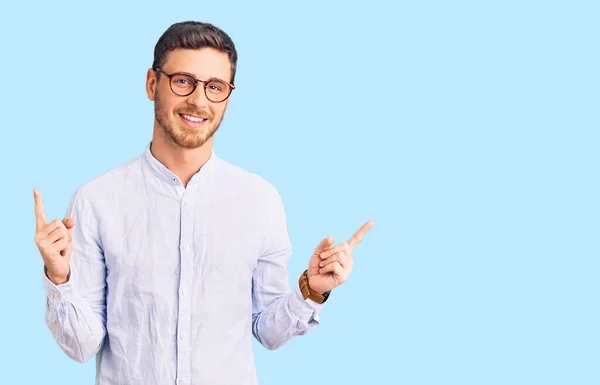 英俊的年轻人 身穿优雅的商务衬衫 戴着眼镜 面带微笑 自信地用手指指向不同的方向 复制广告空间 — 图库照片