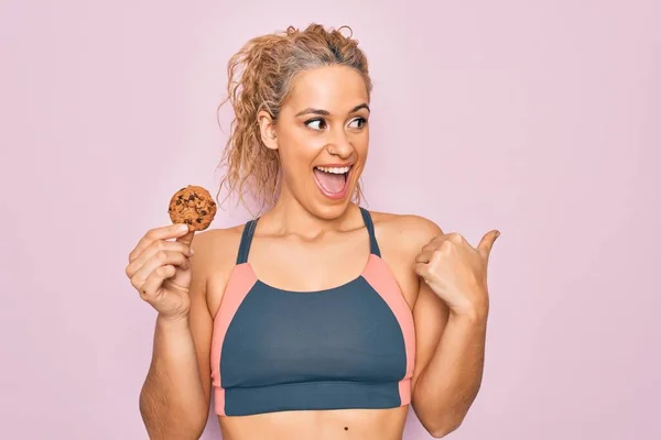 Joven Hermosa Rubia Deportista Haciendo Deporte Sosteniendo Galleta Sobre Fondo — Foto de Stock