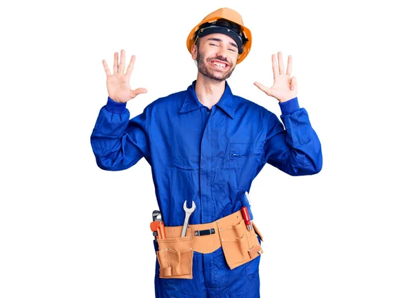 自信と幸せ笑顔ながら若いですヒスパニック男身に着けている労働者の制服を見せ 指番号9で指摘します — ストック写真