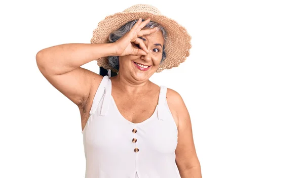 夏の帽子と夏の服を身に着けている灰色の髪を持つシニア女性笑顔幸せな行いますOk Signとともに手で目を通して見る指 — ストック写真