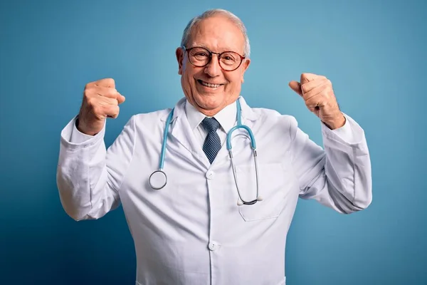 Starszy Siwowłosy Lekarz Noszący Stetoskop Płaszcz Medyczny Niebieskim Tle Pokazujący — Zdjęcie stockowe