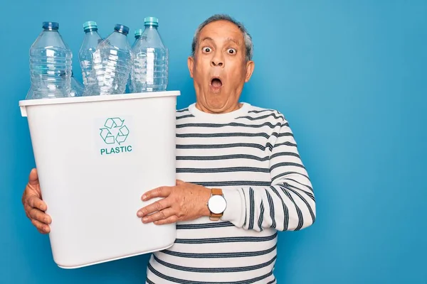 プラスチック製のボトルでゴミ箱を保持している高齢者のリサイクルは 驚きの顔でショックで怖がって青い背景をリサイクルすることができます 恐怖の表現で恐れと興奮 — ストック写真