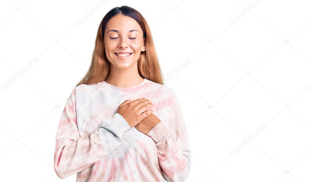 Beautiful young woman wearing casual tie dye sweatshirt smiling with hands on chest with closed eyes and grateful gesture on face. health concept. 