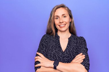 Mor arka planda duran güzel sarışın kadın kollarını kavuşturup kameraya bakarken gülümsüyor. pozitif kişi. 