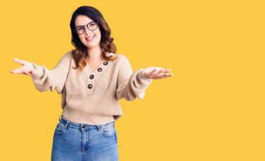 Güzel, genç, esmer bir kadın, günlük kıyafetler ve gözlük takıyor, gülümsüyor, yardım eli uzatıyor ve kabul ediyor.. 