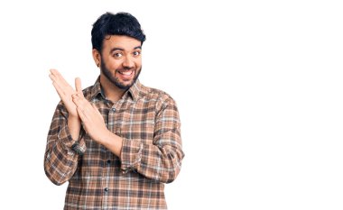 Latin asıllı genç adam, günlük kıyafetler giyip alkışlıyor ve mutlu, neşeli ve gururlu elleri bir arada alkışlıyor. 