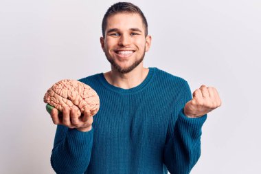 Beyni tutan yakışıklı genç adam gururla haykırıyor, zaferi kutluyor ve başarıyı kollarını kaldırarak kutluyor. 