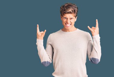 Genç, yakışıklı, günlük kıyafetler giymiş, çılgın bir ifadeyle bağıran, elleri havada rock sembolü yapan bir adam. Müzik yıldızı. ağır kavram. 