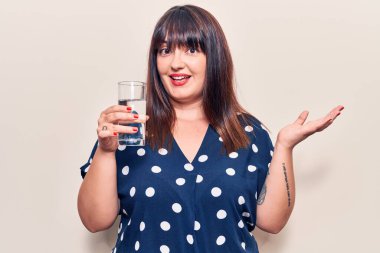 Genç ve cüsseli bir kadın bir bardak su içerek başarıyı mutlu bir gülümsemeyle ve kazanan yüz ifadesiyle kutluyor. 