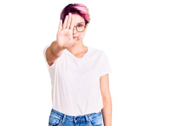 Pembe saçlı, günlük kıyafetler giyen ve gözlük takan genç ve güzel bir kadın avucunun içi gibi şarkı söylemeyi kesiyor. Yüzünde olumsuz ve ciddi bir jest olan uyarı ifadesi. 