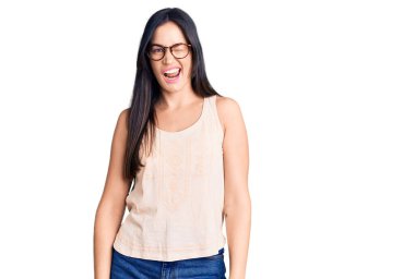 Gündelik kıyafetler ve gözlük takmış genç beyaz bir kadın kameraya seksi bir ifadeyle bakıyor, neşeli ve mutlu bir yüz.. 