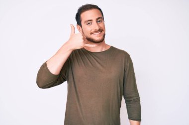 Genç, yakışıklı, sıradan kıyafetler giymiş, gülümseyen, el ve parmaklarıyla telefonla konuşan bir adam. iletişim kavramları. 