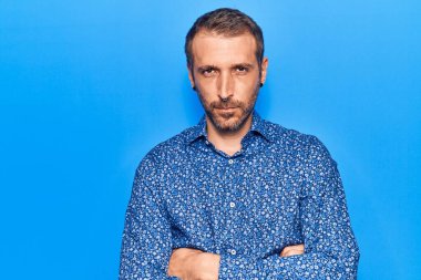 Gündelik kıyafetler giyen, kuşkucu ve gergin genç yakışıklı bir adam. Yüzünde çapraz kollarla onaylamayan bir ifade var. negatif kişi. 