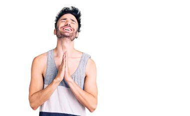 Gündelik giysiler giyen genç İspanyol adam elleri bağlı yalvarıyor ve dua ediyor. Yüzünde umut ifadesi var. Çok duygusal ve endişeli. Yalvarıyor. 