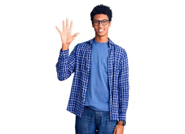 Genç Afro-Amerikalı günlük kıyafetler ve gözlük takmış beş numaralı parmaklarıyla işaret ederken kendinden emin ve mutlu bir şekilde gülümsüyor.. 