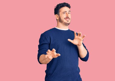 Gündelik kıyafetler giyen genç İspanyol adam tiksinti ifadesi takındı, tiksinti tepkisi yüzünden tiksinti ve korku dolu bir ifade takınıyordu. Eller havada. 