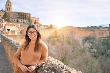 Genç, güzel, esmer, gözlüklü, mutlu ve kendinden emin bir kadın. Yüzünde tebessümle şehrin duvarına yaslanarak duruyorum.