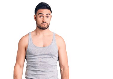 Mayolu, kolsuz tişörtlü, kuşkucu ve gergin genç bir adam sorun yüzünden surat asıyor. negatif kişi. 