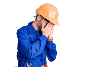 Ağlarken yüzünü ellerle kapatan üzgün yüzlü İspanyol işçi üniforması giyen genç bir adam. depresyon kavramı. 