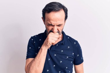 Sıradan polo giyen orta yaşlı yakışıklı bir adam izole edilmiş beyaz arka planda kendini iyi hissetmiyor ve soğuk algınlığı veya bronşitin belirtisi olarak öksürüyor. Sağlık hizmeti kavramı.