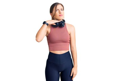 Güzel beyaz kadın spor kıyafetleri giyiyor ve kulaklık takıyor. Bıçak niyetine boğazını kesiyor. Saldırganlıkla tehdit ediyor. 