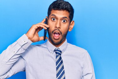 Genç latin adam akıllı telefondan konuşuyor korkmuş ve şaşırmış bir şekilde ağzı açık, inançsız bir yüz. 