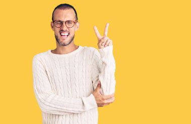 Gündelik kıyafetler ve gözlük takan genç yakışıklı adam kameraya bakıp gülümsüyor ve zafer işareti yapıyor. İki numara.. 