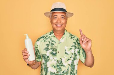 Orta yaşlı, kır saçlı, yaz şapkalı, elinde güneş koruması kremi olan yaşlı bir adam bir fikir ya da soru işareti ile şaşırdı.