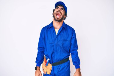 Kıvırcık saçlı yakışıklı genç adam ve ayı gibi giyinen tamirci üniforması kızgın, kızgın ve öfkeli çığlıklar atan, öfkeyle bağıran. öfke ve agresif konsept. 