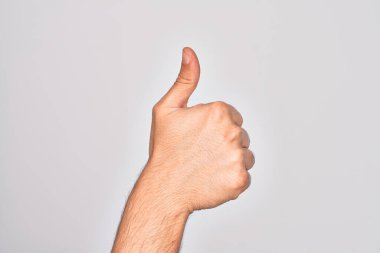 Beyaz arka planda parmaklarını gösteren beyaz tenli bir gencin eli başarılı bir onay hareketi yapıyor. Başparmak işareti, onay ve olumlu bir sembol ile.