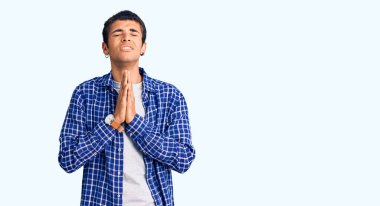 Genç Afro-Amerikan bir adam günlük giysiler giyip elleri bağlı yalvarıyor ve dua ediyor. Yüzünde umut ifadesi var. Çok duygusal ve endişeli. Yalvarıyor. 