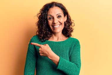 Orta yaşlı, güzel bir kadın, sıradan bir süveter giyiyor. Gülümsüyor, eli ve parmağı yana doğru uzanıyor. 