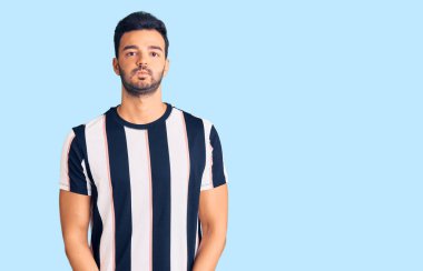 Çizgili tişört giyen, komik yüzlü, yanak şişiren genç, yakışıklı İspanyol adam. Havayla şişmiş ağız, çılgın bir ifade.. 