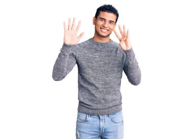 Hispanik yakışıklı genç adam gündelik süveter giyer ve dokuz numarayı göstererek gülümserken kendinden emin ve mutlu.. 