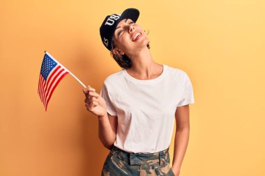 Amerika Birleşik Devletleri bayrağı taşıyan genç ve güzel bir kadın. Pozitif ve mutlu görünüyor. Kendine güvenen bir gülümsemeyle dişlerini gösteriyor. 