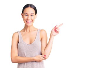 Güzel, esmer, rahat bir elbise giyen, gülümseyen, mutlu, eli ve parmağı yanda olan bir kadın. 