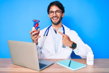 Yakışıklı, doktor üniforması giyen, kalbi tutan, mutlu, eli ve parmağı olan bir İspanyol. 