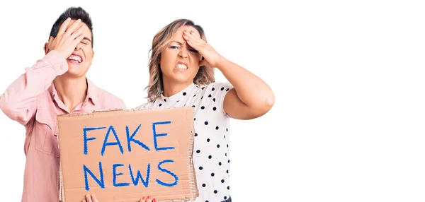 Couple Women Holding Fake News Banner Stressed Frustrated Hand Head — Stock Photo, Image